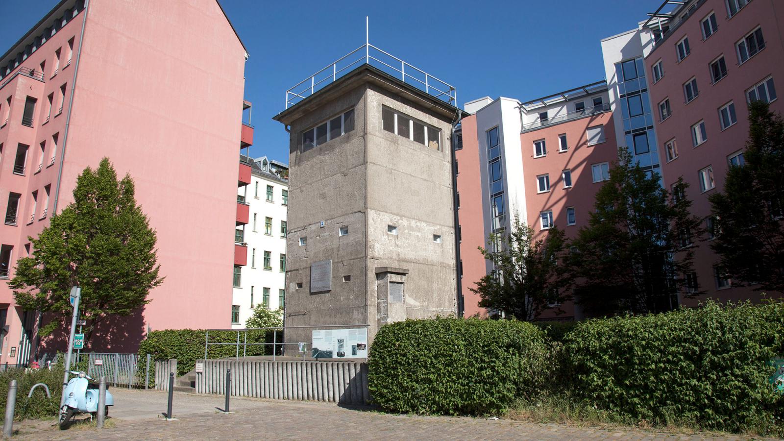 Der Wachturm der Gedenkstätte zwischen neu gebauten Häusern