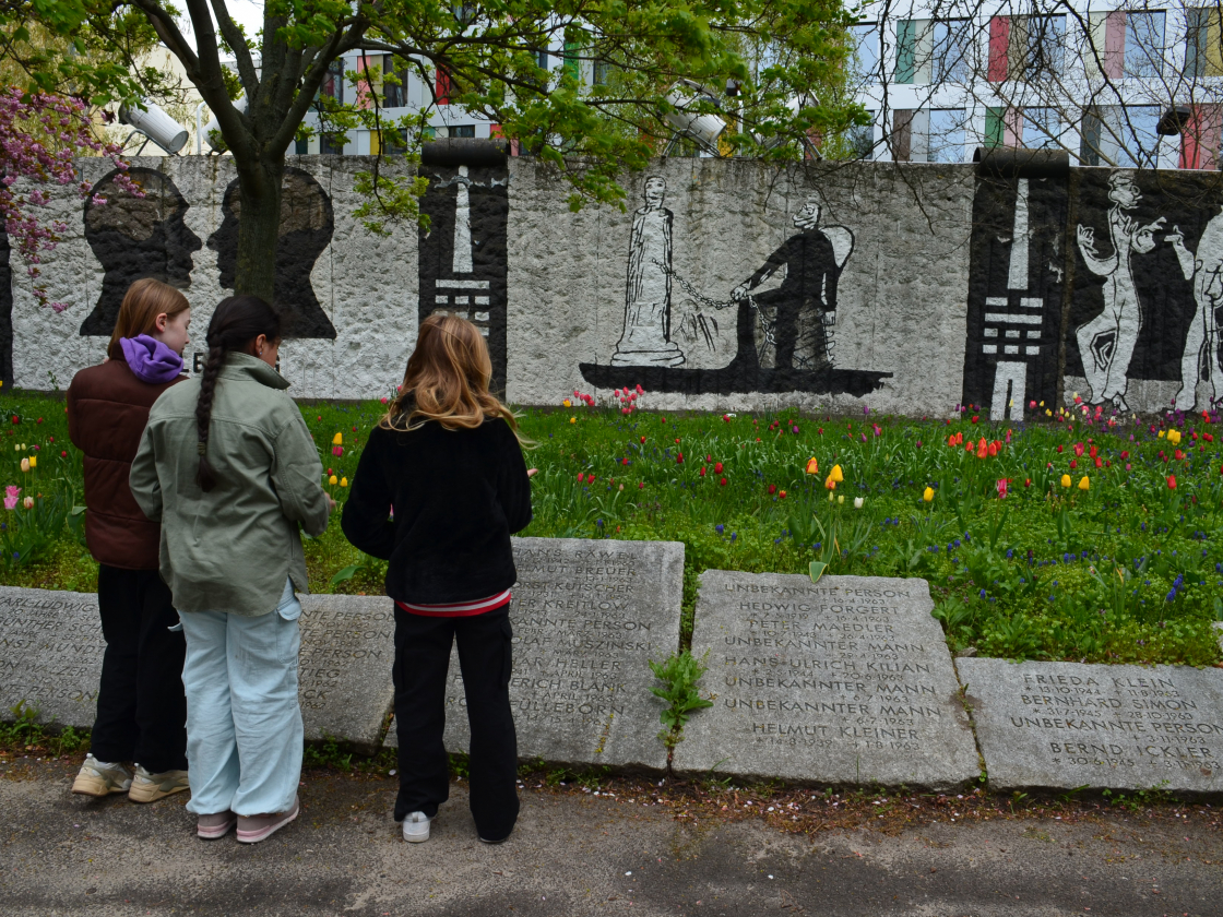 drei Kinder stehen vor den Gedenktafeln am Parlament der Bäume