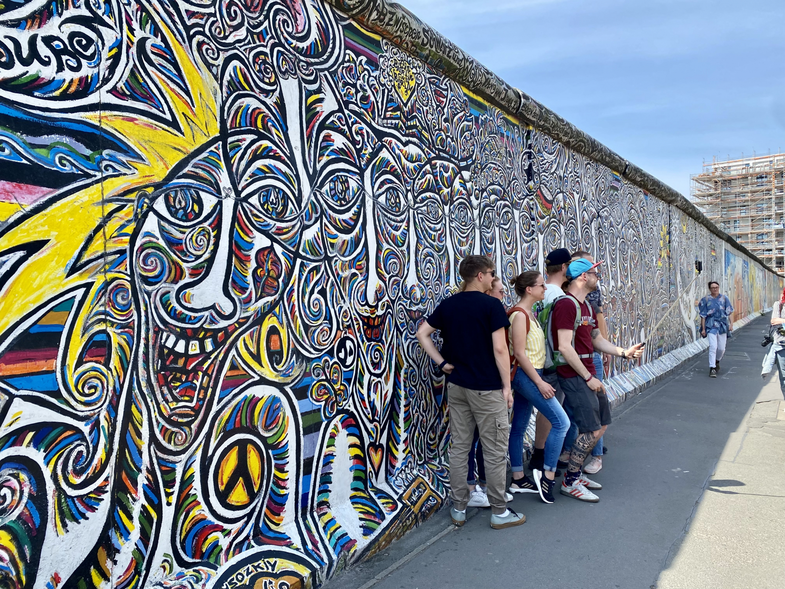 Besuchende vor einem Wandbild an der East Side Gallery