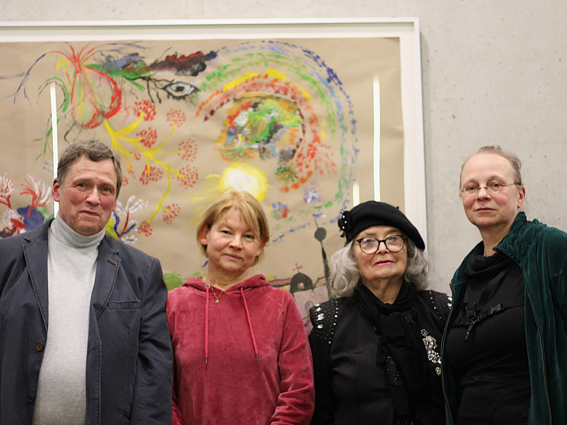 Vier Personen posieren vor einem Gemälde an der Wand