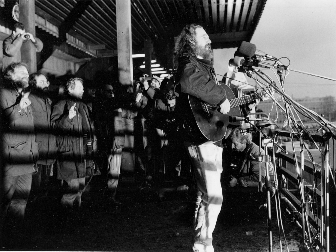 Ein Sänger spielt Gitarre auf einer Bühne vor einer Menschenmenge