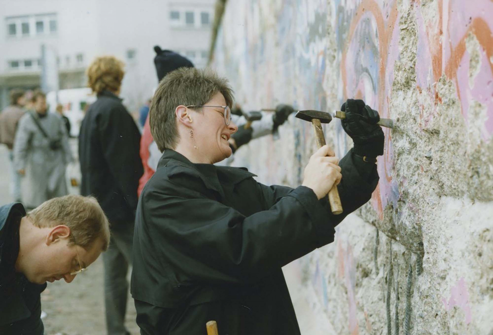 Personen schlagen Stücke aus der Mauer heraus