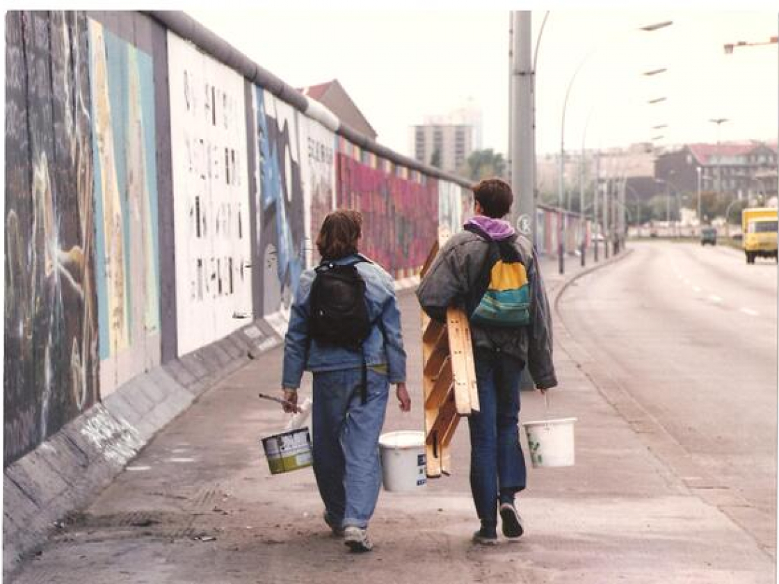 Zwei Personen laufen an der East Side Gallery entlang